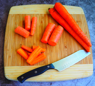 Sliced carrots on a cutting board with a knife