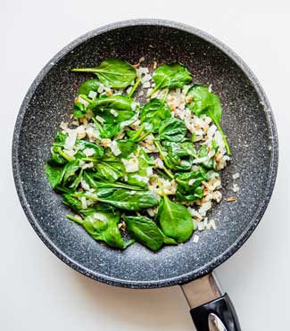 Sauteed Onions and Spinach in a skillet 