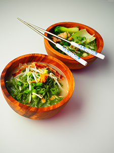 Two wooden bowls of healthy ramen on a white table
