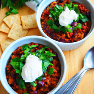 Bison Chili with Beans in two bowls topped with sour cream